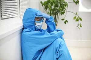 Tired depressed nurse in personal protective equipment PPE after difficult shift during Covid-19. photo