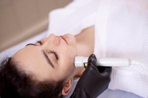 Closeup of face of beautiful relaxing girl undergoing hardware cosmetology procedure in spa photo