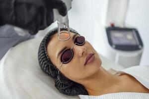 Closeup of the face of young woman undergoing laser resurfacing and peeling procedure in spa salo photo
