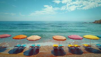 Brightly colored umbrellas are arranged on a sandy beach against the backdrop of clear turquoise water and rocky outcrops. A picturesque and inviting seaside scene. photo