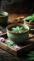 Cup of herbal tea with a cannabis leaf floating on it, surrounded by additional cannabis leaves and buds on a wooden tray photo