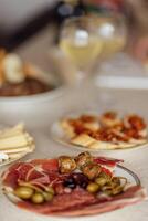 Two glasses of cool champagne and plates with various snacks on a table photo