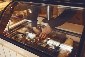 Hands og a ma with a scoop ice cream from the refrigerator and an attendant in a waffle cone photo