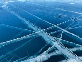 Texture of beautiful blue ice with cracks and air bubbles in the frozen lake photo