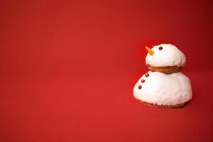 A little cute snowman made of cookies and white cream with chocolate buttons and eyes. Bright red background. Minimalism. Christmas holiday celebrate concept. Happy New Year eve atmosphere. photo