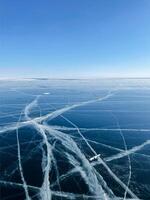 Texture of beautiful blue ice with cracks and air bubbles in the frozen lake photo
