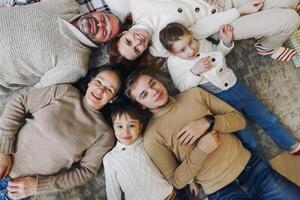 Top view of happy big multi-generation family lying in circle on floor and smiling at camera photo