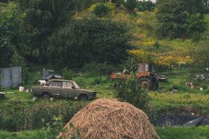 A rustic courtyard. A haystack. In the background is an old car and a tractor photo