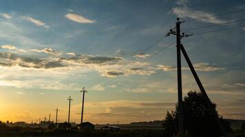 Supports of power lines extending into the distance into the field. Eevening photo