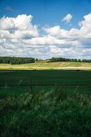 Thick clouds over green fields. The highway is far beyond the field photo