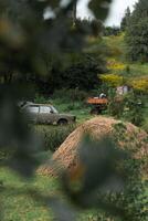 A rustic courtyard. A haystack. In the background is an old car and a tractor photo