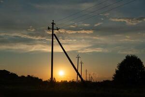 Supports of power lines extending into the distance into the field. Eevening photo