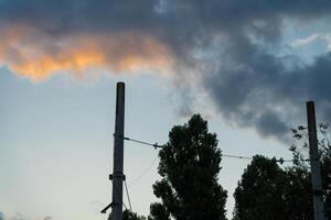 Poles of power lines against the background of sunset clouds photo