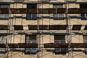 Scaffolding stands against the wall of the building. Restoration of the building photo