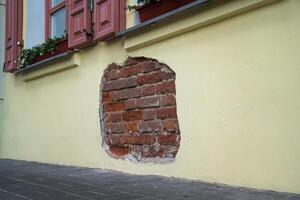 The fallen plaster from the wall of the building from under which the brickwork is visible photo