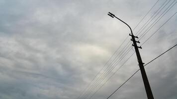 A lamppost with wires on the background of a cloudy dense sky. Grey, cloudy weather photo