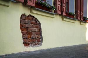 The fallen plaster from the wall of the building from under which the brickwork is visible photo