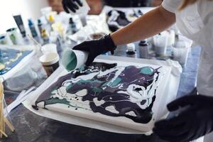 Master class on an Acrylic Fluid Pouring. Young women paint with liquid acrylic in an art workshop photo