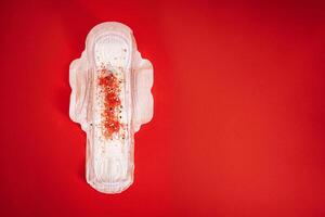 Menstrual pad with red and silver sequins on a red background, free space for text photo