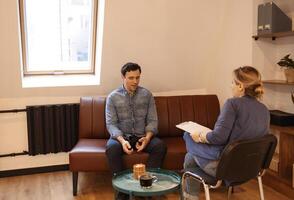 Nice serious pleasant man visiting a psychologist and having a psychological session while dealing with problems in relationships photo