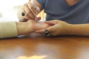 Palm Reading. Chiromancer drawing life lines on female plam during palmistry or chiromancy session photo