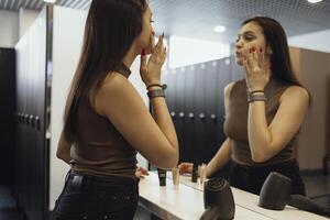 a woman is looking in the mirror while applying makeup photo