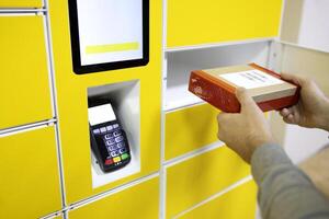 Close up of a man picks up mail from automated self-service post terminal machine photo