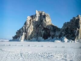 a large rock formation on the shore of a frozen lake photo