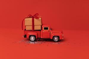 Miniature car with Christmas decoration on red bright background with sparkles and confetti photo