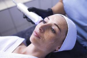 Closeup of face of beautiful relaxing girl undergoing hardware cosmetology procedure in spa photo