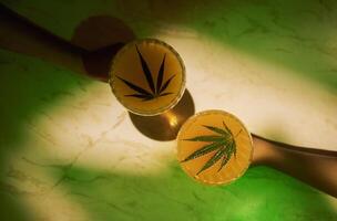 Two outstretched hands with elegant glasses with delicious cocktails with cannabis leaves on the marble surface of the table. Tasty healthy juice with hemp on a background with neon light. photo