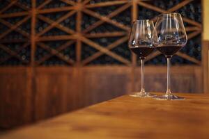 Wine bottles on a wooden shelf. Wine bar. Two glasses with red wine on wooden background photo