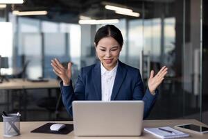 Businesswoman in office looking confused while working on laptop computer. Professional woman trying to solve problem during workday. Office worker in suit dealing with work challenge. photo