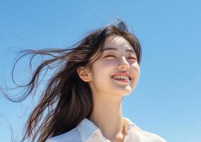 Beautiful woman smiling hair blowing in the wind blue sky background. photo
