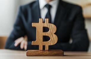 Wooden sign bitcoin on a table in front of a businessman isolated over a white background. photo