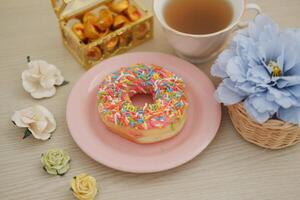 pink plate with a donut and a cup of tea on top, perfect for a cozy afternoon snack. photo