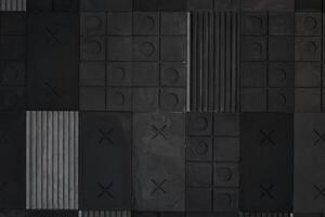 Textured gray and black geometric background made of concrete, paste with stripes, squares, circles, crosses, tic-tac-toe, copy space. Concept of abstract modern wall design with bulky convex elements photo