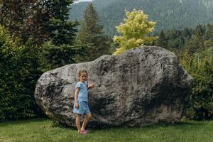 cute girl walks among the mountains and big stones in the Alps in summer photo