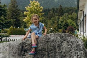 cute girl sitting on top of a big stone in the Alps in summer photo