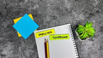 Concept of Imposter Syndrome write on sticky notes isolated on Wooden Table. photo