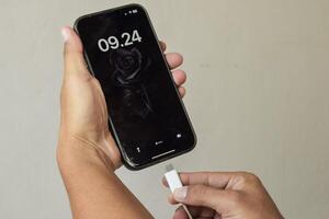 Mobile smart phones charging. Man hands plugging a charger in a smartphone photo