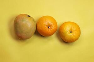 Orange Fruit and mango fruit on a Yellow table. photo