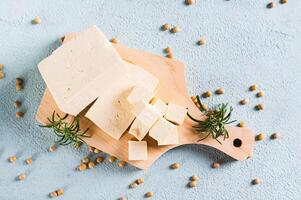 Close up of fresh sliced soy cheese tofu and rosemary on a wooden board on the table top view photo