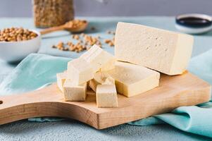 Cubes of fresh organic tofu cheese with rosemary on a board close-up photo