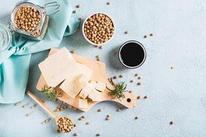 Fresh sliced soy cheese tofu and rosemary on a wooden board on the table top view photo