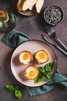 Baked egg and bacon rolls with basil on a plate on a table top and vertical view photo