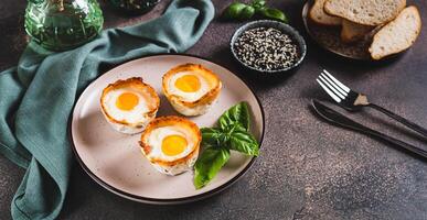 Chicken eggs baked in bacon and basil leaves on a plate on the table web banner photo