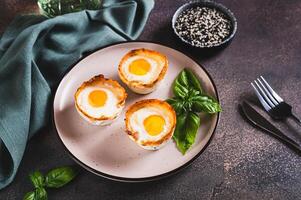 Baked egg and bacon rolls with basil on a plate on a table photo