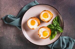 Close up of chicken eggs baked in bacon and basil leaves on a plate on the table top view photo