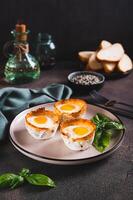 Chicken eggs baked in bacon and basil leaves on a plate on the table vertical view photo